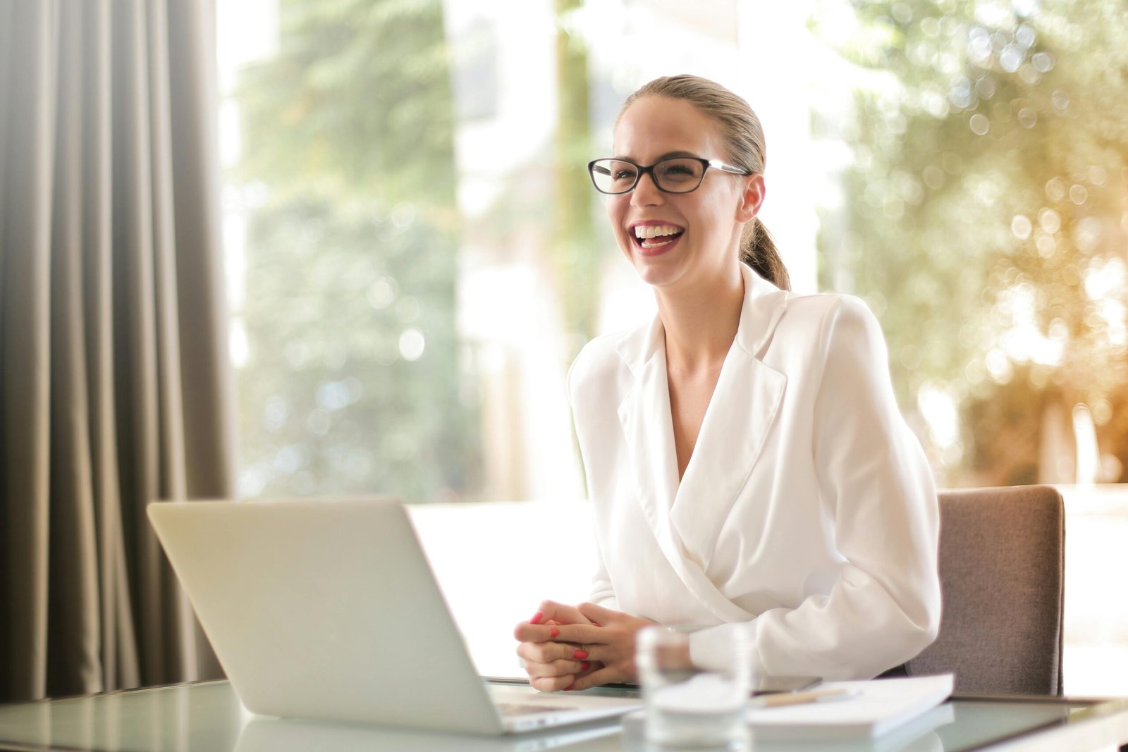 work in spain Smiling professional woman in formal attire working on a laptop—representing successful applicants securing a Spanish work visa with expert guidance from Gazelle Immigration Group.